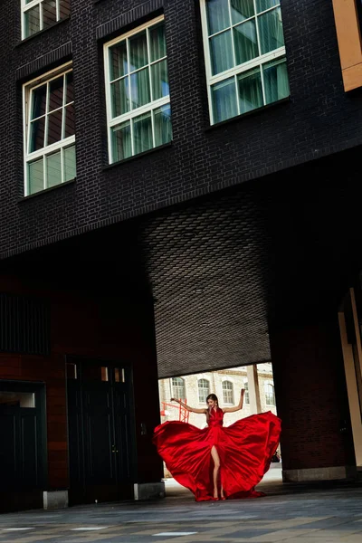 Young gorgeous woman in long red dress posing in modern city — Stock Photo, Image