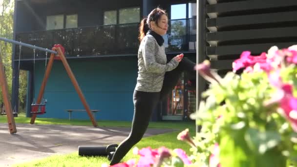 Young woman stretching legs outdoors near apartments building — Stock Video