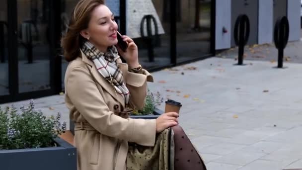 Hermosa mujer de negocios con abrigo beige hablando en el teléfono móvil — Vídeos de Stock