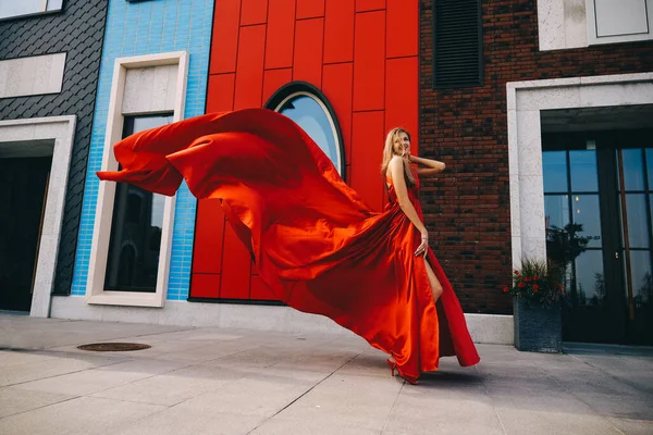 Jonge prachtige vrouw in lange rode jurk poseren in moderne stad — Stockfoto