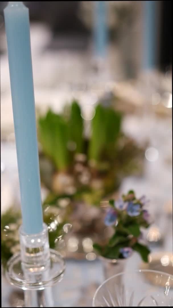 白と青の色でクリスマステーブルの設定。ガラス製品、キャンドル、天然の花のクローズアップ — ストック動画