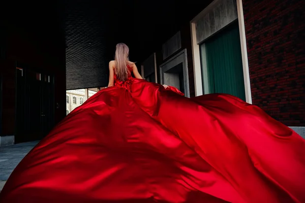 Jovem mulher linda em vestido vermelho longo andando na cidade — Fotografia de Stock