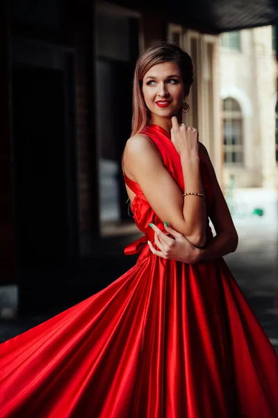 Ung vacker kvinna i lång röd klänning i modern stad — Stockfoto