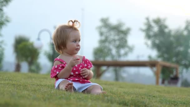 Çimlerin üzerinde oturmuş karpuz yiyen tatlı bir kız. — Stok video