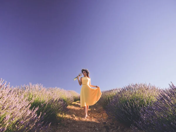 노란색 옷을 입고 라벤더 들판에서 부케와 함께 서 있는 아름다운 여인 — 스톡 사진