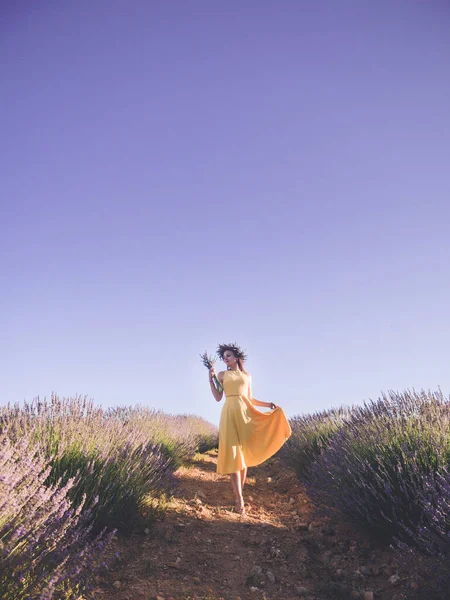 Beautiful woman in yellow dress standing with bouquet in lavender field — Stock Photo, Image