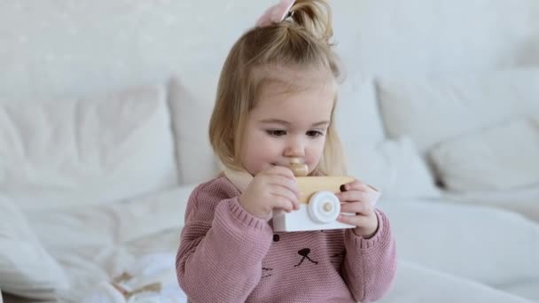 Klein schattig meisje spelen met houten speelgoed camera — Stockvideo