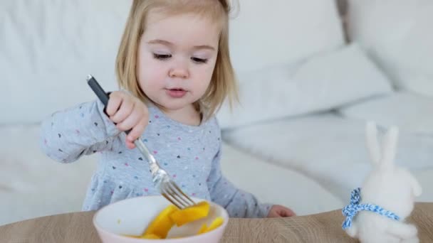 Adorável menina de um ano e meio comendo pedaços de manga — Vídeo de Stock