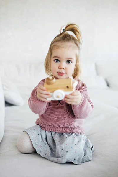 Pequena menina adorável segurando câmera de brinquedo de madeira — Fotografia de Stock