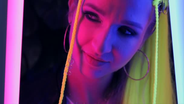 Millenniumi fiatal nő sárga haj divatos neon rózsaszín és kék fények. — Stock videók