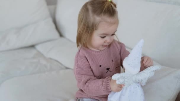 Красивая маленькая девочка играет с белой куклой — стоковое видео
