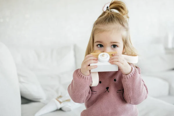 Pequena menina adorável segurando câmera de brinquedo de madeira — Fotografia de Stock