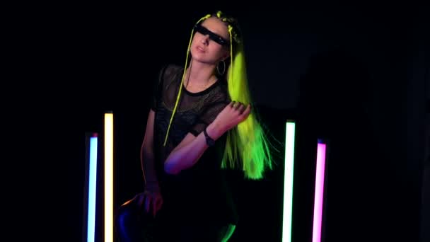 Young attractive woman with yellow hair sitting near colorful neon tube lights — 비디오