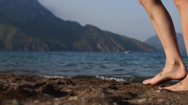 Λεπτή γυναίκα ταξιδιώτης με τα πόδια ξυπόλητη κατά μήκος κύματα θάλασσα στην αμμώδη παραλία. — Αρχείο Βίντεο