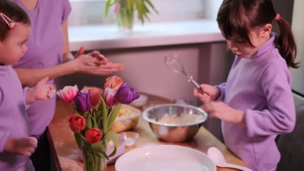 母親と2人の子供の娘がアップルパイを調理する 女の子は卵黄を生地に入れます キッチンで一緒にパン屋を準備している幸せな家族 自家製の食べ物と小さなヘルパー — ストック動画