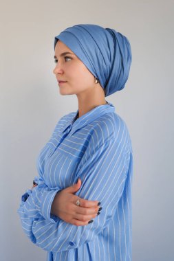 Gri arka planda modern tarz mavi başörtüsü takan genç Müslüman kadının yan görünüm yüzü