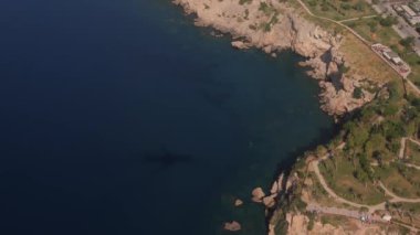 View from airplane window to an airplane shadow on the sea and land, city roofs close to Antalya airport