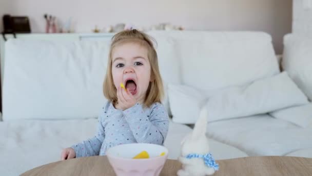 漂亮的一岁半小女孩穿着可爱的衣服 用叉子吃芒果片 — 图库视频影像