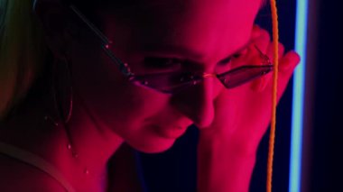 Modern gözlüklü, parlak kırmızı ve pembe ışıklı çekici genç kadın gözleri. Modaya uygun neon portre.. 