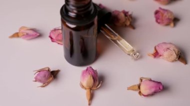 Beauty moisturizing essence in oil dropper glass bottle in rotation. Dry rose petals around.