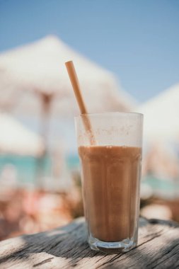 Plajda buzlu kahve. Plaj barında, deniz kenarında samanla birlikte uzun bardakta buzlu kahve.