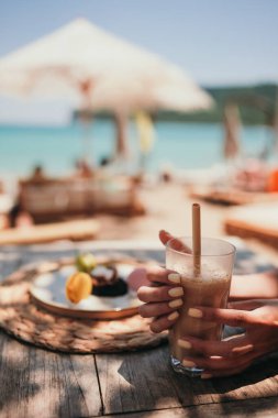 Plajda buzlu kahve. Büyük bardakta buzlu kahve, deniz kenarında saman, plajda kahve, latte.. 