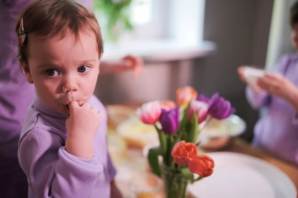 Little toddler girl licking her finger. Cooking with family together at the kitchen. Little helpers