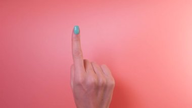 Close up of womans hand with blue manicure counting from one to five with her fingers on pink background