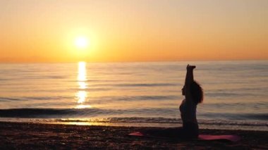 Young woman stretching near the sea during sunrise time. Stretching in the morning for increasing inner energy.