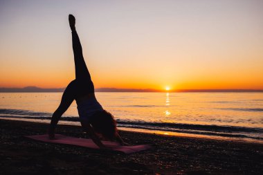 Young woman stretching near the sea during sunrise time. Stretching in the morning for increasing inner energy.