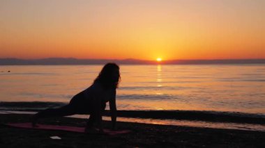 Young woman stretching near the sea during sunrise time. Stretching in the morning for increasing inner energy.