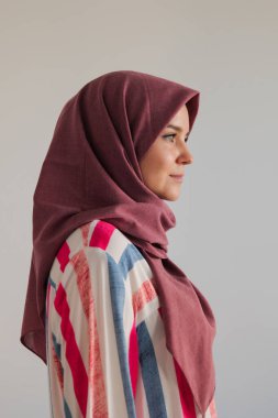 Gri arka planda güzel kırmızı başörtüsü takan Müslüman kadının yan görünüm yüzü