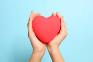 Kırmızı kalp çocukların ellerinde mavi bir arkaplanda