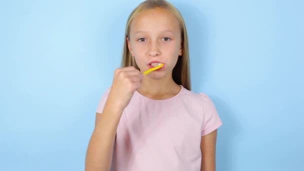 The girl brushes her teeth on a blue background close-up. Oral care — Stock Video