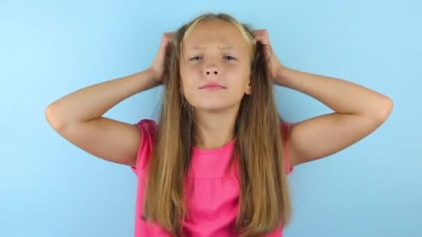Chica se rasca la cabeza sobre un fondo de color — Vídeos de Stock