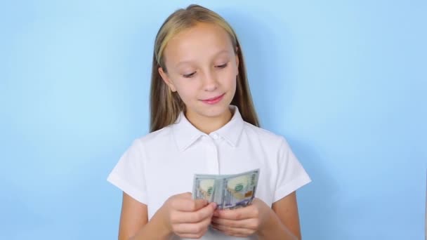 Chica sosteniendo el dinero en las manos sobre un fondo azul de cerca — Vídeos de Stock