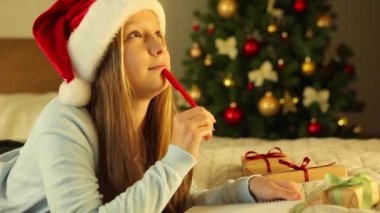 Noel için dekore edilmiş bir iç mekandaki çocuk Noel Baba 'ya bir mektup yazar.