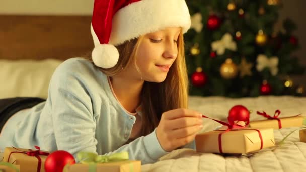 Ребенок дома в интерьере, оформленном на Рождество открывает праздничные подарки — стоковое видео