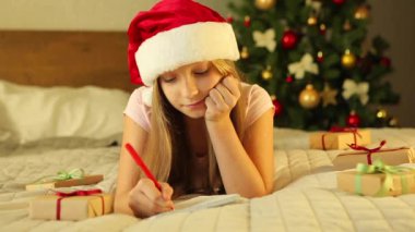 Noel için dekore edilmiş bir iç mekandaki çocuk Noel Baba 'ya bir mektup yazar.
