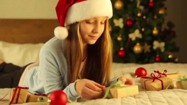 Noel için dekore edilmiş bir evde çocuk bayram hediyelerini açıyor. 