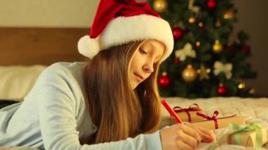 Noel için dekore edilmiş bir iç mekandaki çocuk Noel Baba 'ya bir mektup yazar.