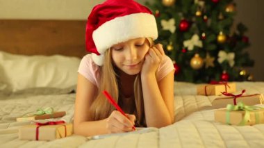 Noel için dekore edilmiş bir iç mekandaki çocuk Noel Baba 'ya bir mektup yazar.