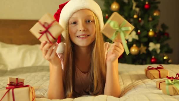 Дитина вдома в інтер'єрі, прикрашеному Різдвом, відкриває святкові подарунки — стокове відео