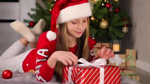 Criança em casa em um interior decorado para Natal envolve presentes de férias — Vídeo de Stock