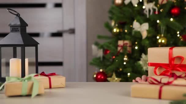 La chica mira a la mesa donde yacen los regalos de Navidad — Vídeo de stock