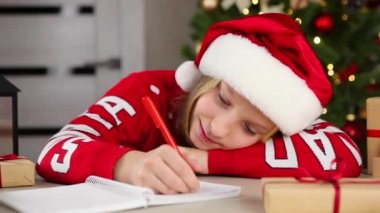 Noel için dekore edilmiş bir iç mekandaki çocuk Noel Baba 'ya bir mektup yazar.