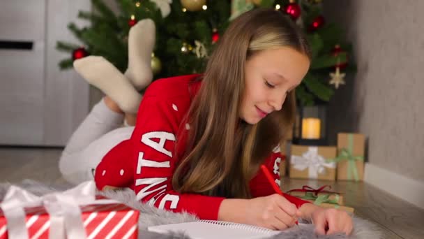 Kind in een versierd interieur voor Kerstmis schrijft een brief aan de kerstman — Stockvideo