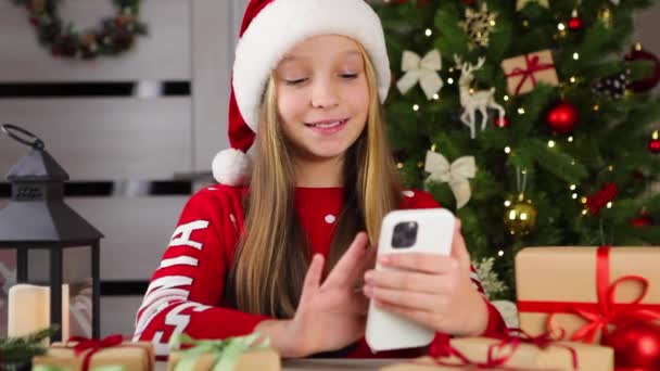 Дівчина спілкується через відео виклик за допомогою смартфона в різдвяному інтер'єрі — стокове відео