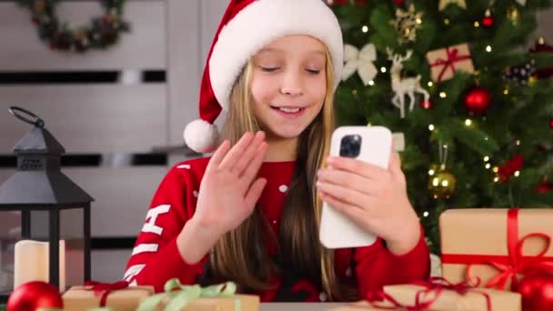 Chica se comunica a través de videollamada utilizando el teléfono inteligente en el interior de Navidad — Vídeo de stock