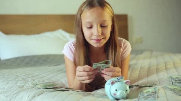 Teenager girl puts bills in piggy bank piggy bank in home interior — Stock Video